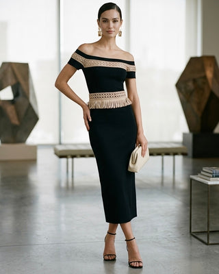 Woman wearing a black off-shoulder dress with beige lace details in an indoor setting.