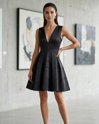Woman wearing a black dress in an indoor setting with abstract art on the wall.