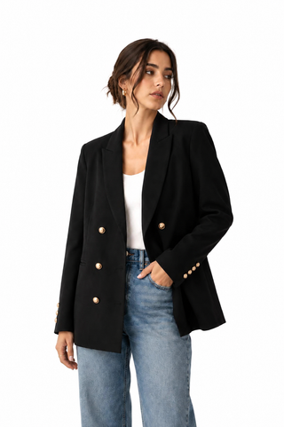 Woman wearing a black blazer with gold buttons and light blue jeans on a white background
