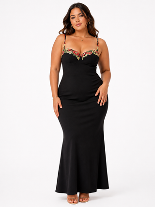 Woman wearing a black evening gown with floral embellishments on a white background