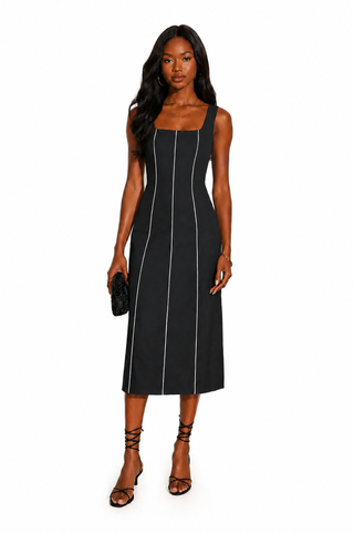 Woman wearing a black sleeveless dress with white stripes on a white background