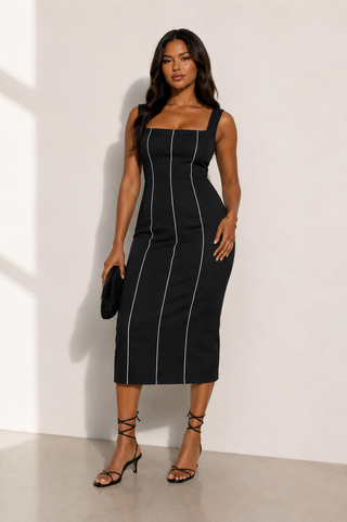 Woman wearing a black dress with white stripes against a white background