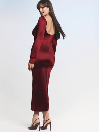 Woman wearing a burgundy dress with a backless design on a light gray background