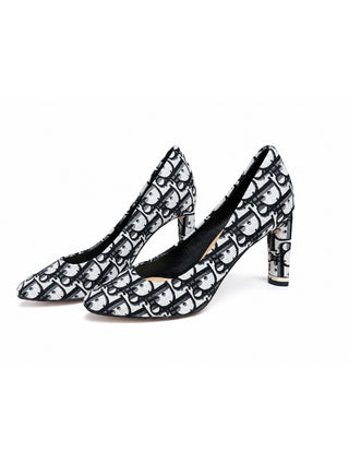 A pair of pointed-toe high heels with a black and white repeating monogram pattern, displayed on a clean white background.