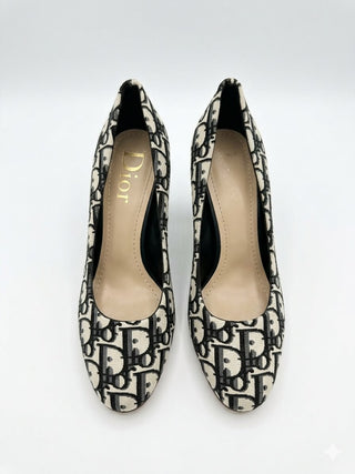 A pair of Dior pointed-toe pumps featuring the signature Dior Oblique monogram pattern in black and beige, with a beige insole displaying the gold Dior logo.