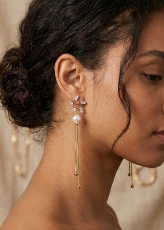 Close-up of a woman wearing a gold earring with a pearl drop.