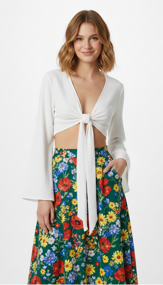 Woman wearing a white tie-front top and colorful floral skirt on a white background