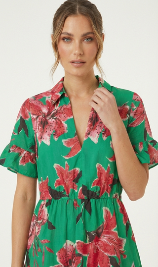 Woman wearing a green floral dress with red flowers on a white background