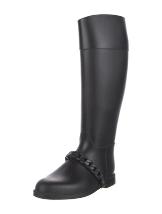 A single black knee-high rain boot with a decorative braided strap detail around the ankle, shown against a plain white background.