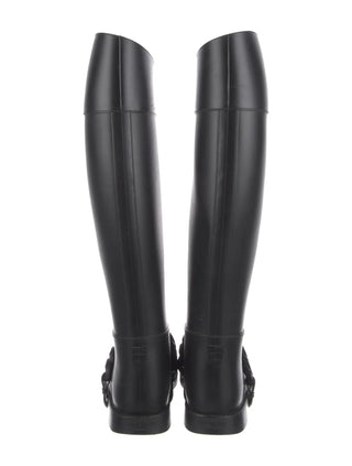 Black equestrian riding boots shown from the back, featuring a glossy finish and decorative buckle details at the heel, set against a plain white background.