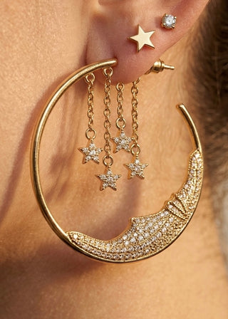 Gold hoop earring with star charms worn by a person