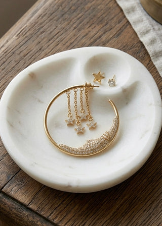 Gold earrings on a marble dish with a wooden background