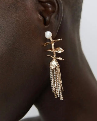 Gold earrings with tassels and pearls worn by a person