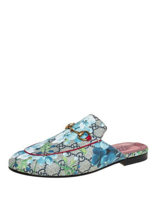 A Gucci slip-on mule loafer featuring a blue and green floral print over the brand's signature GG monogram canvas, with a gold horsebit detail on the strap and a pink insole.
