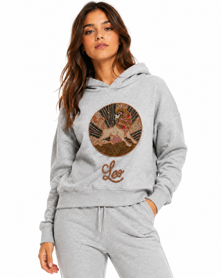 Woman wearing a gray hoodie with a 'Leo' design on a white background