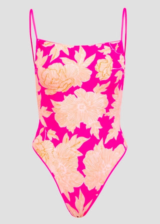 A bright pink one-piece swimsuit with a large peach and cream floral print, featuring thin shoulder straps, shown against a solid light gray background.