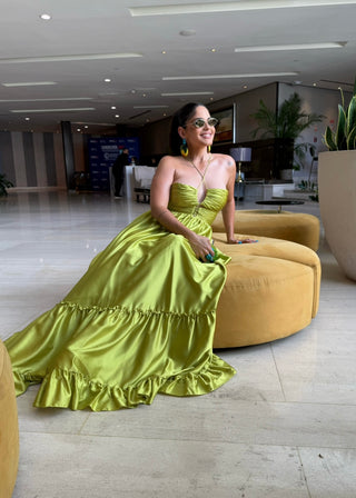 Woman in a green dress sitting on a yellow couch in an indoor setting.