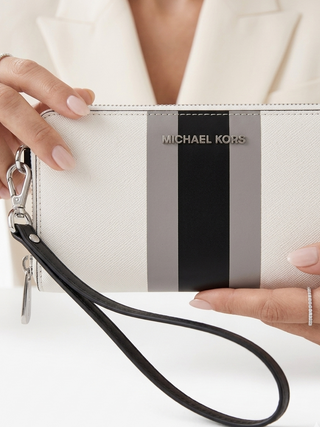 White clutch with black and gray stripes held by a person on a white background