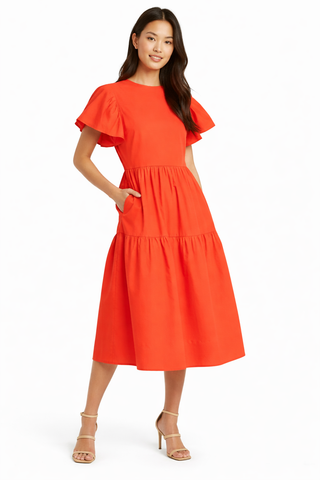Woman wearing an orange dress with ruffled sleeves on a white background