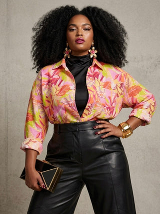 Woman wearing a colorful floral blouse with black pants against a gray background