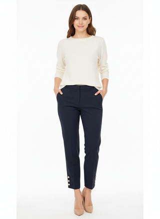 Woman wearing a white sweater and navy pants on a white background
