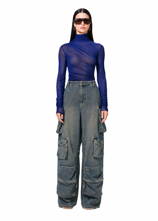 Person wearing a blue sheer top and denim cargo pants on a white background