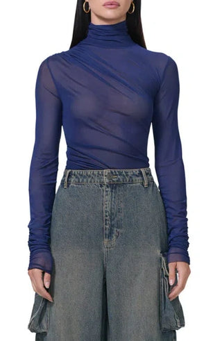 Person wearing a blue sheer turtleneck top and denim skirt on a white background
