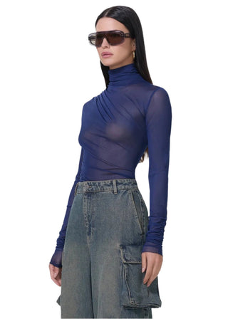 Woman wearing a sheer blue top and wide-leg jeans on a white background