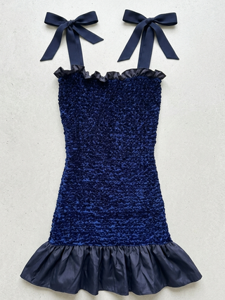 Navy blue dress with ruffled details on a light gray background