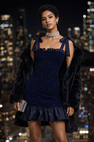 Woman in a dark blue dress with a fur coat against a cityscape background