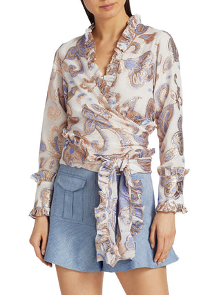Woman wearing a patterned blouse and denim shorts on a white background