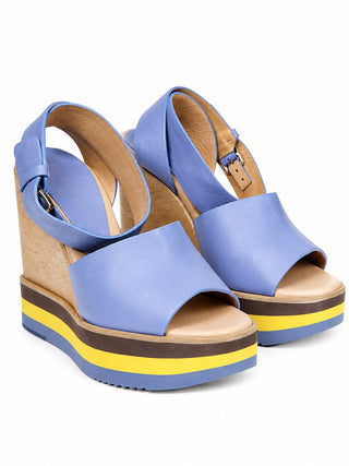 A pair of women's platform wedge sandals in light blue leather with a tan wood-look wedge heel and a thick sole featuring blue, brown, and yellow stripes, shown on a white background.