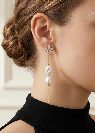 Close-up of a woman wearing a gold earring with pearls and crystals.