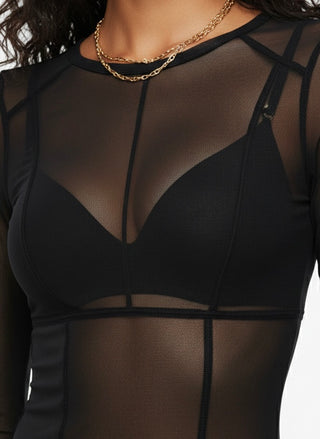 Black sheer top worn by a person with a gold necklace on a white background