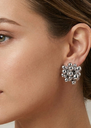 Close-up of a woman wearing silver floral earrings.