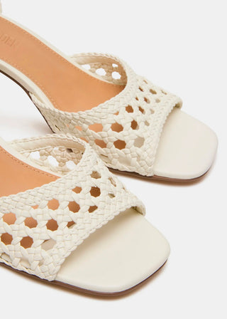 A pair of off-white woven slide sandals with square toes and low block heels, shown on a light gray background.