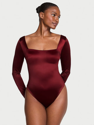 Woman wearing a burgundy bodysuit against a plain background
