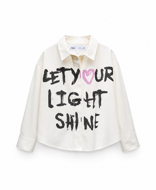 White shirt with text 'LET YOUR LIGHT SHINE' on a white background